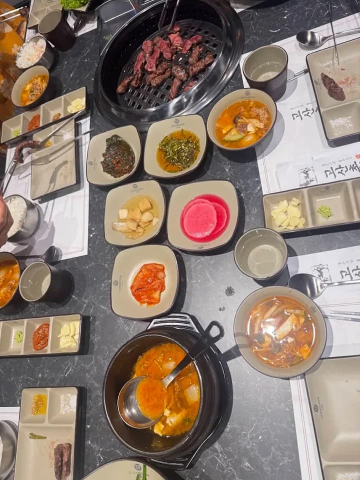 Banchan and stew set out around the grill