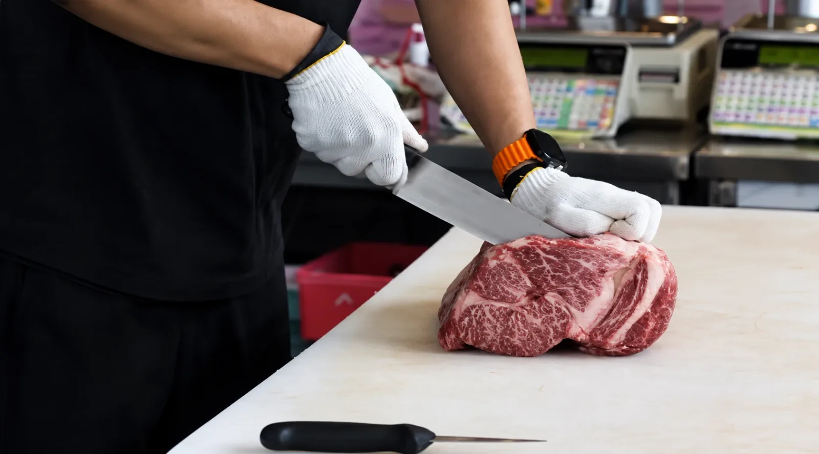 A butcher at the GOSANCHON counter cutting a marbled joint of beef